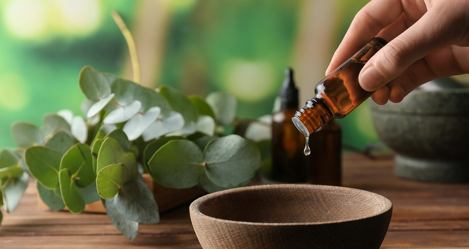 A woman pouring essential oil into a wooden bowl