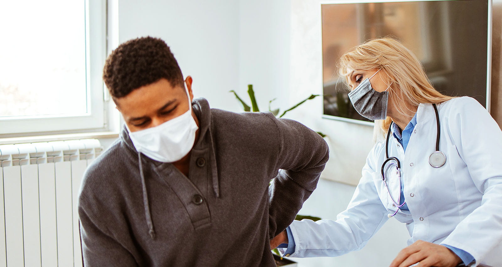 A young African-American is man having his kidney examined by a female doctor in a her office