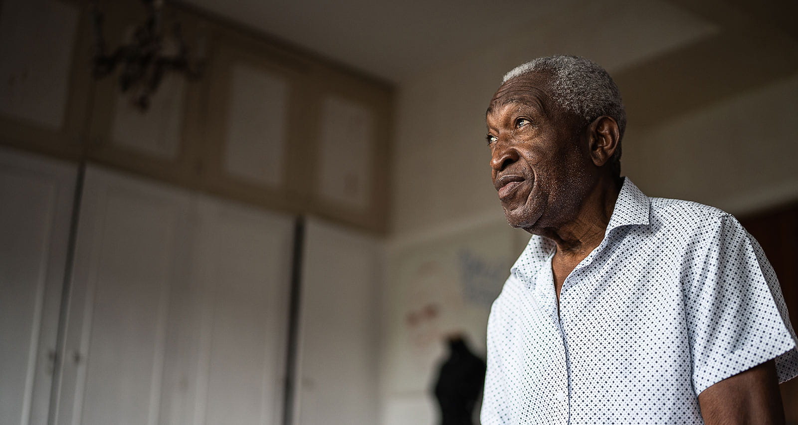 A senior man sitting on a bed and looking away