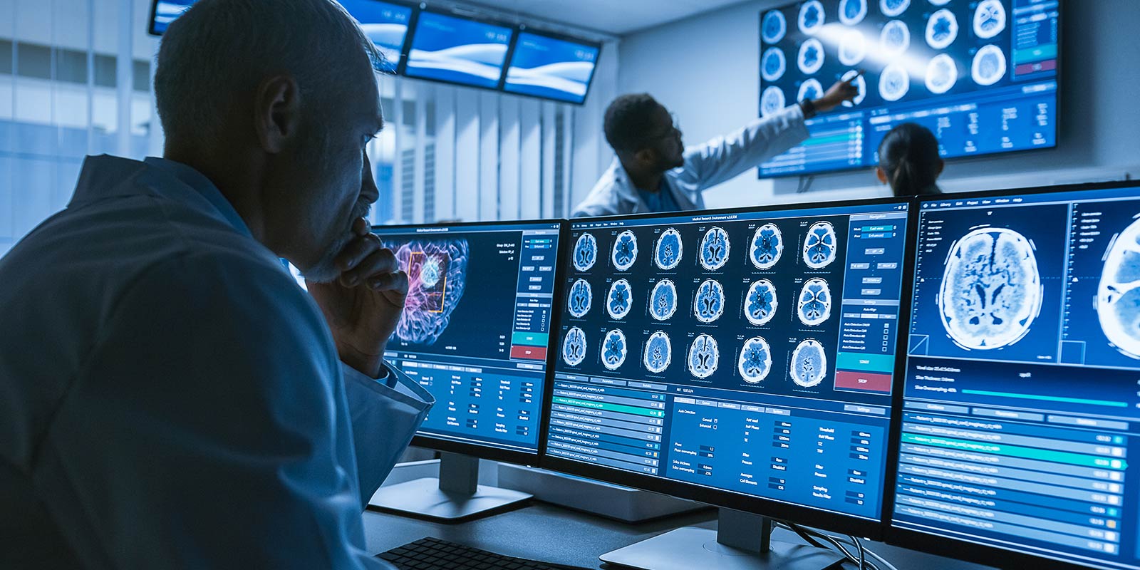Over the Shoulder Shot of Senior Medical Scientist Working with CT Brain Scan Images on a Personal Computer in Laboratory.