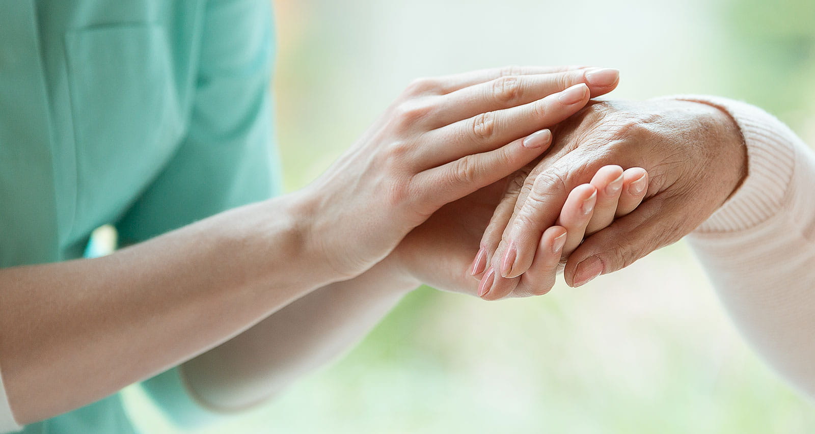 A young caretaker massaging the hand of a patient with Parkinson’s disease
