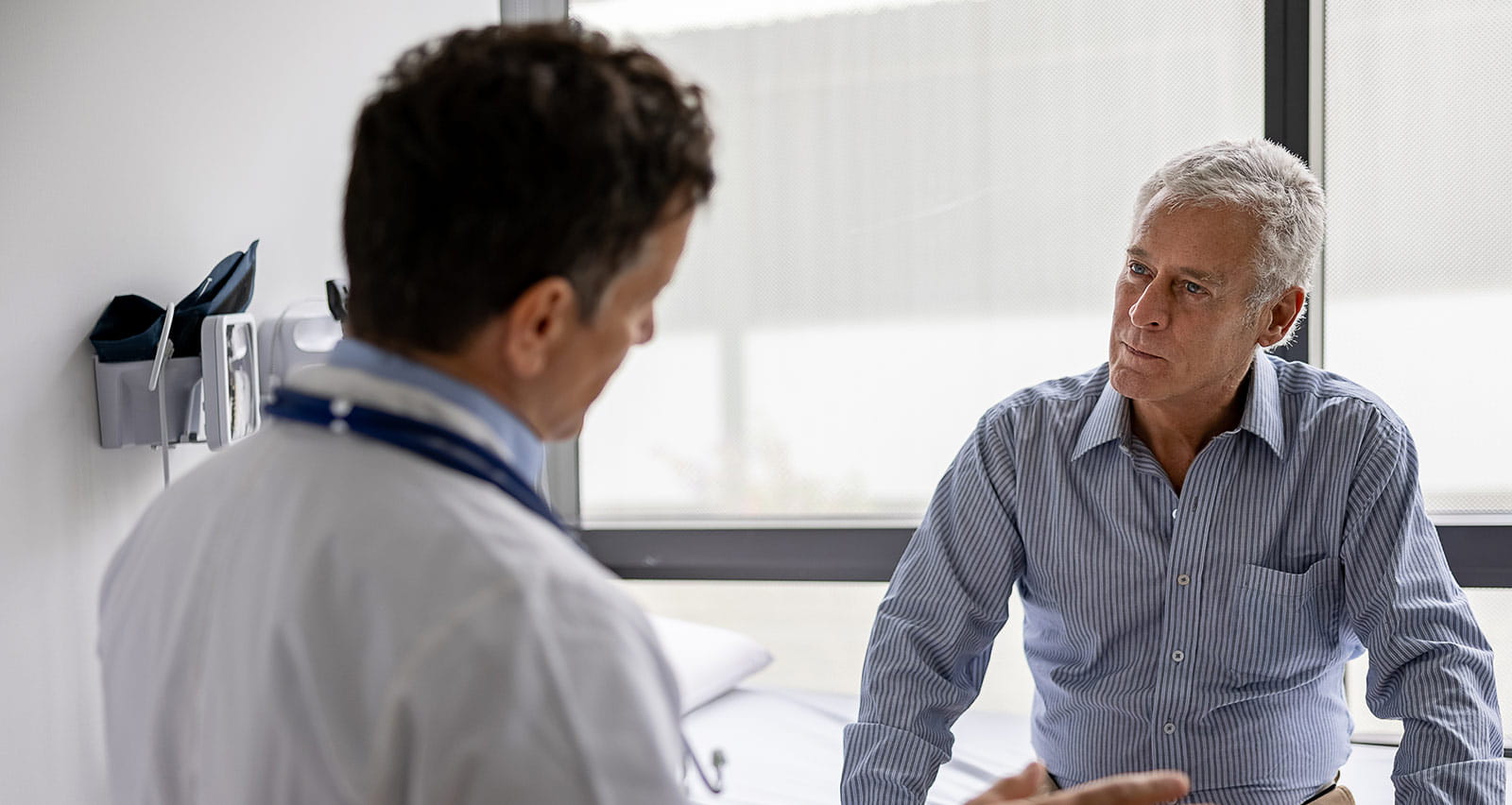 Latin American doctor talking to a patient in a consultation at his office practice