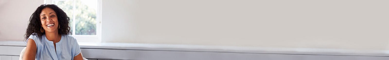 Woman sitting at home smiling.