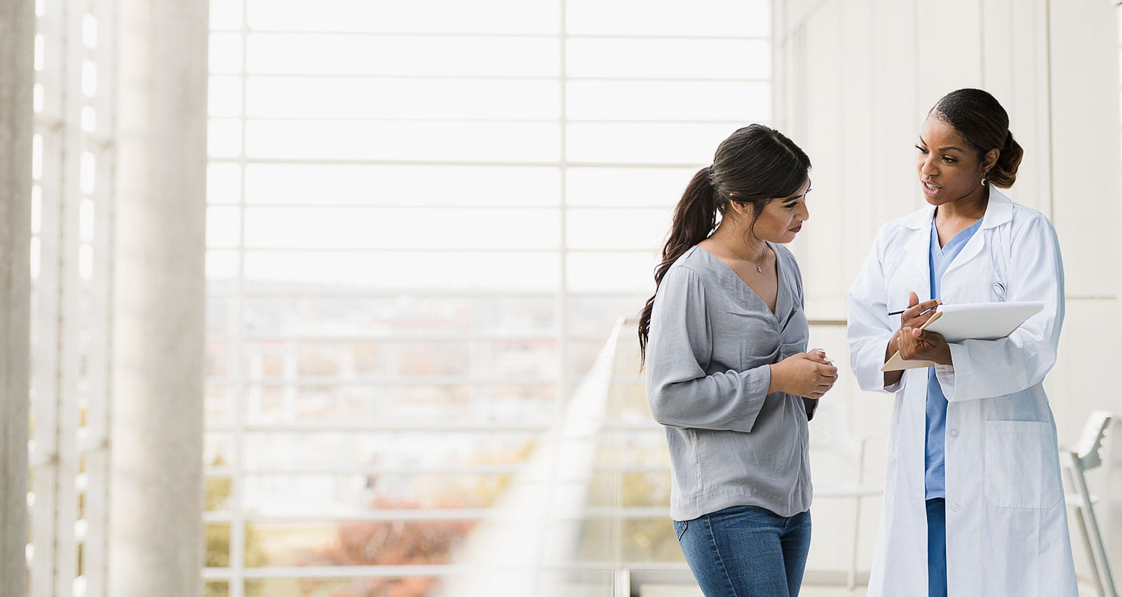 A female doctor explains her patient's test results as they stand in the hospital walkway