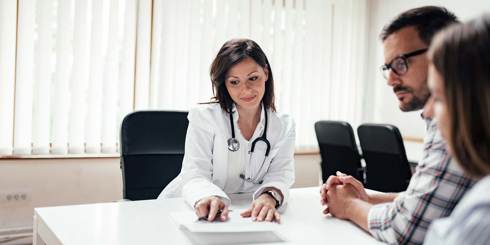 Doctor having discussion with young couple in the clinic