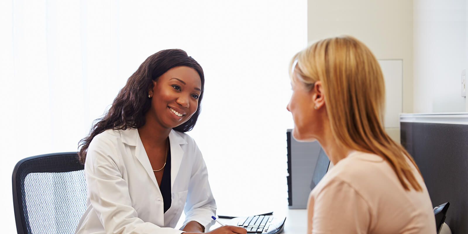 Woman talking to her doctor writing notes.