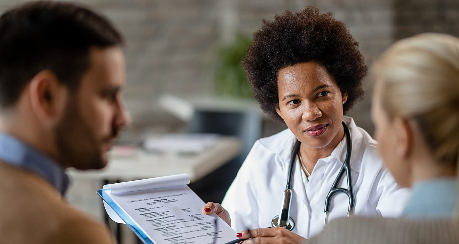 A feamle fertility doctor showing a couple test results of their medical exam at a clinic
