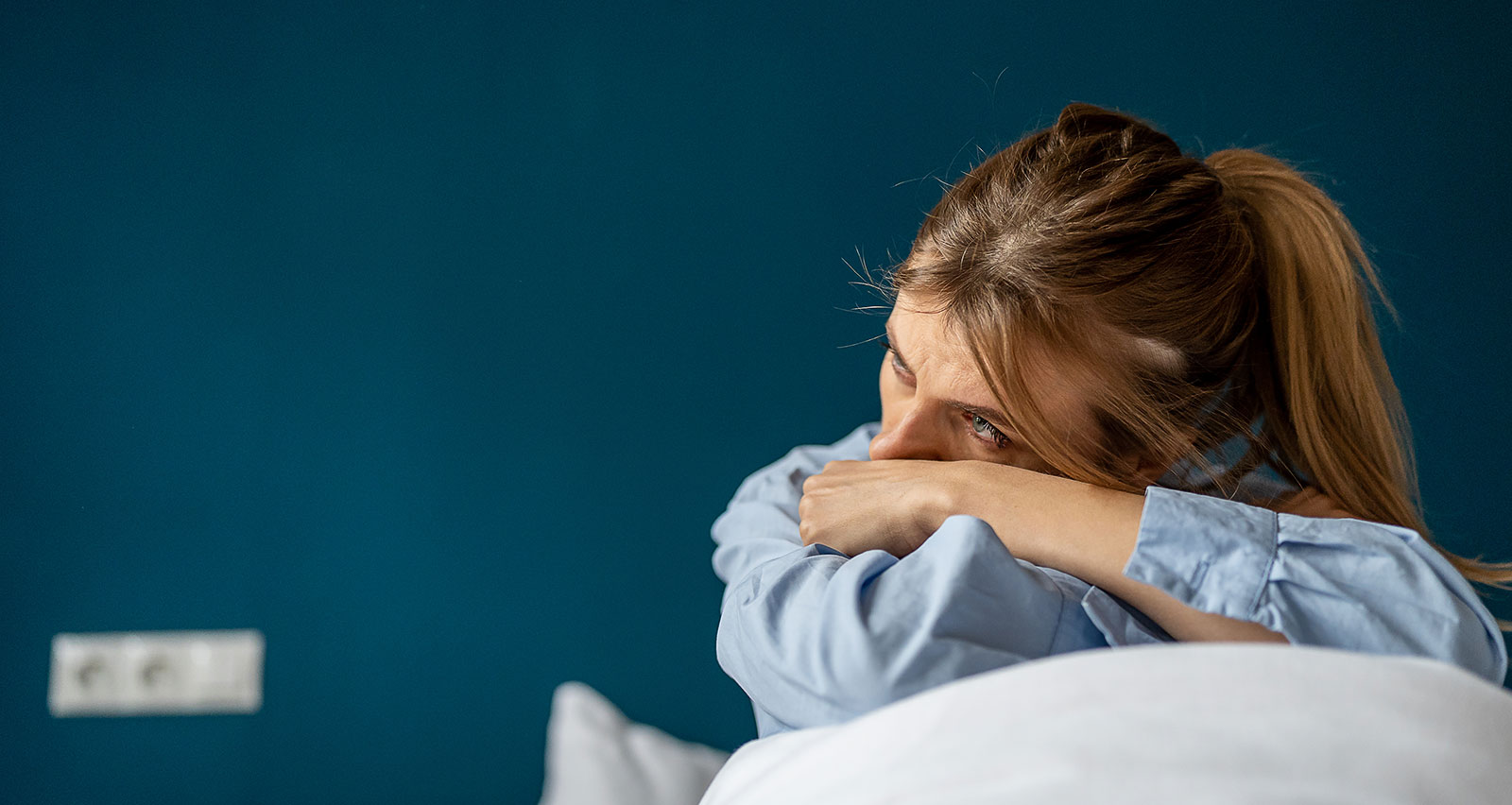 An unhappy woman sitting on a bed looking aside