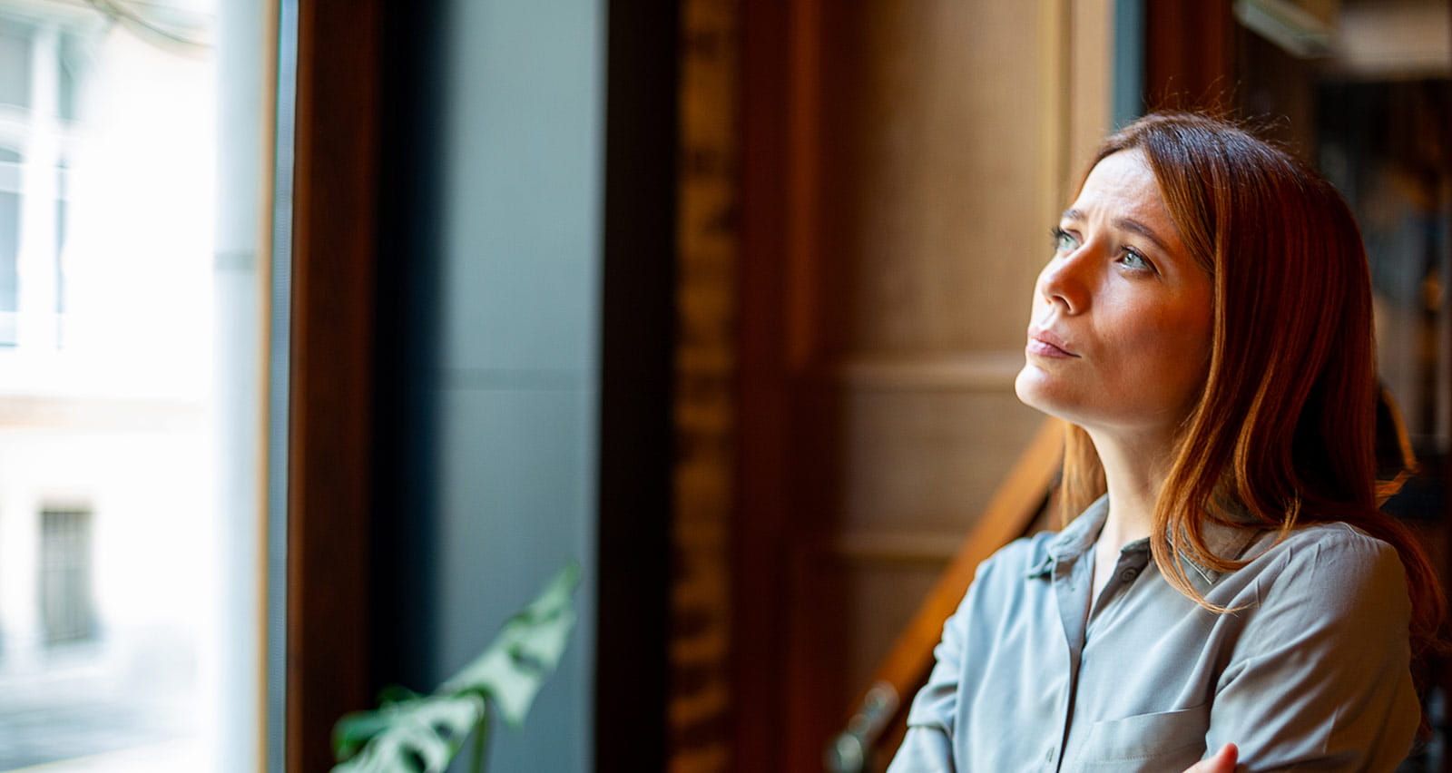 A young adult woman is contemplating by a window