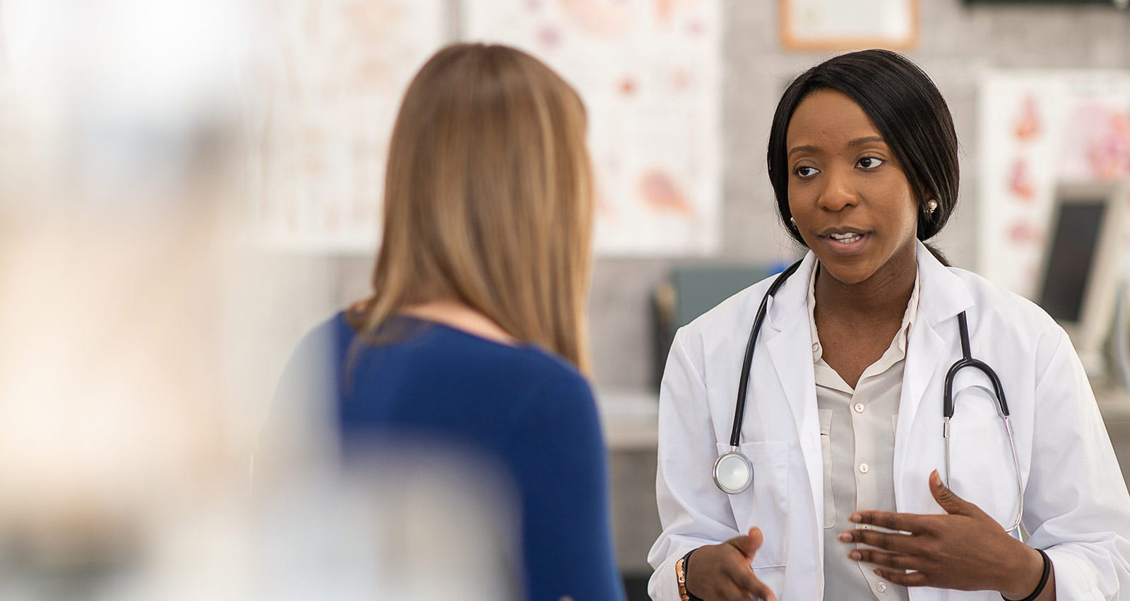 A female OB/GYN provider sits across from her female patient as they talk about her health
