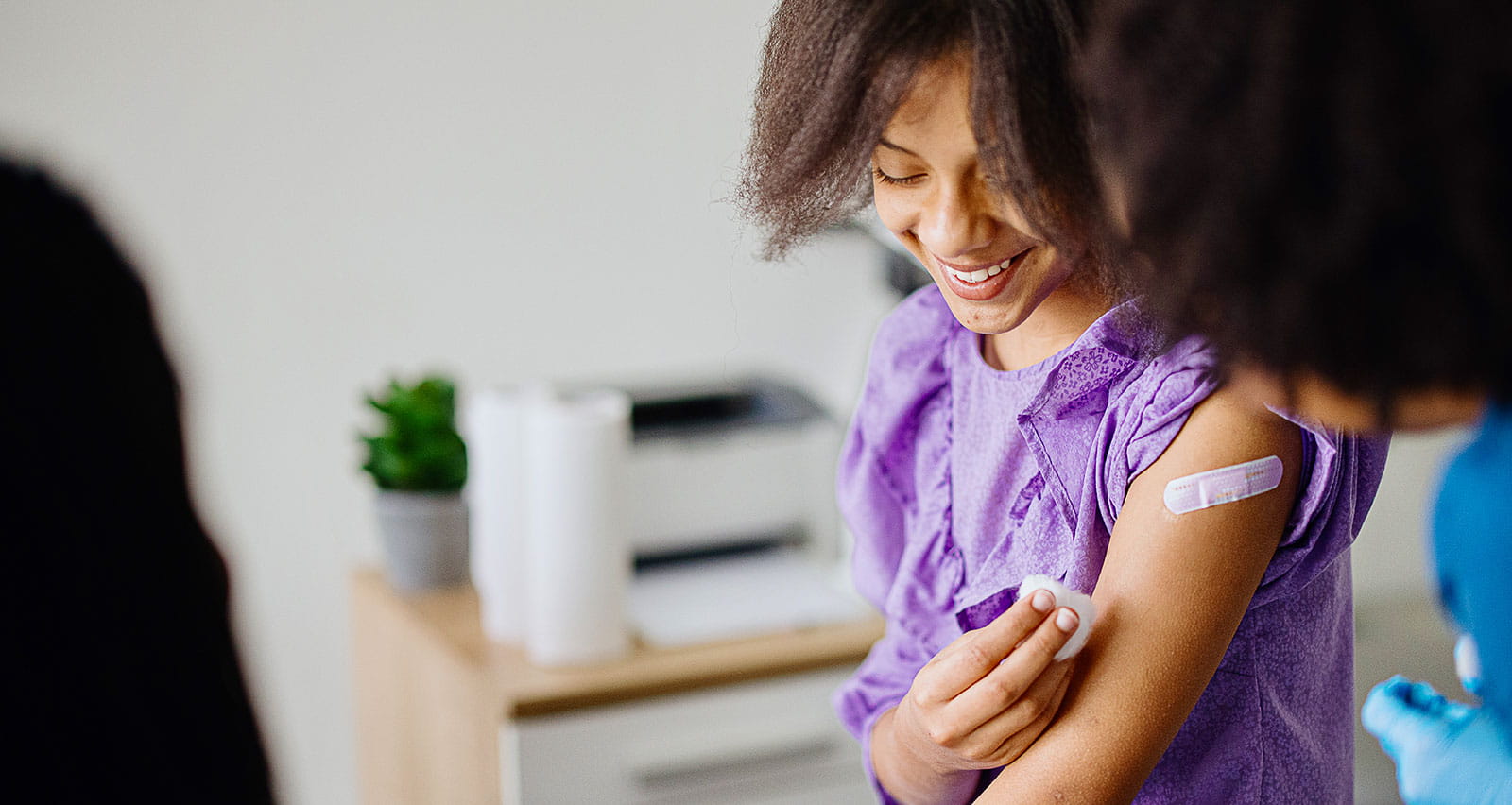 Teen girl getting her HPV vaccine at doctor's office while accompanied by her mother