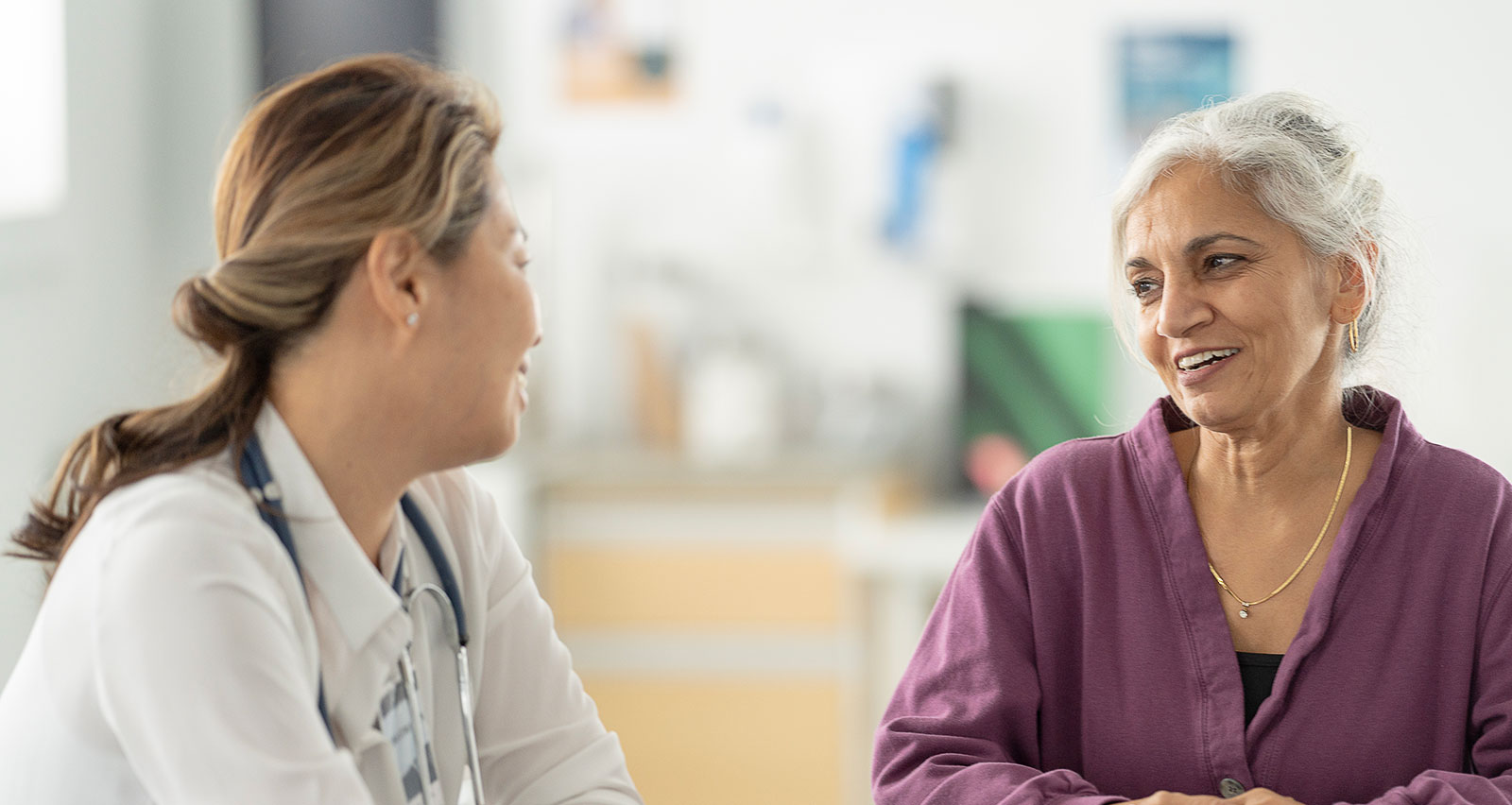 A middle-aged woman sits with her female doctor as they discuss her health concerns