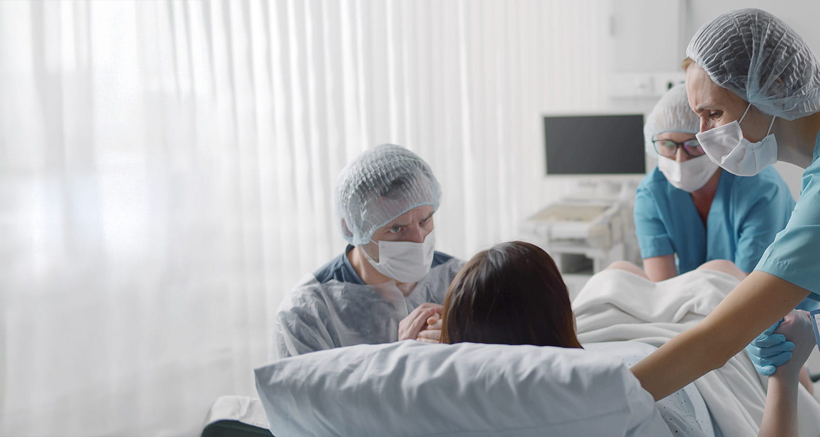 Medical staff in protective gear helping pregnant woman in labor