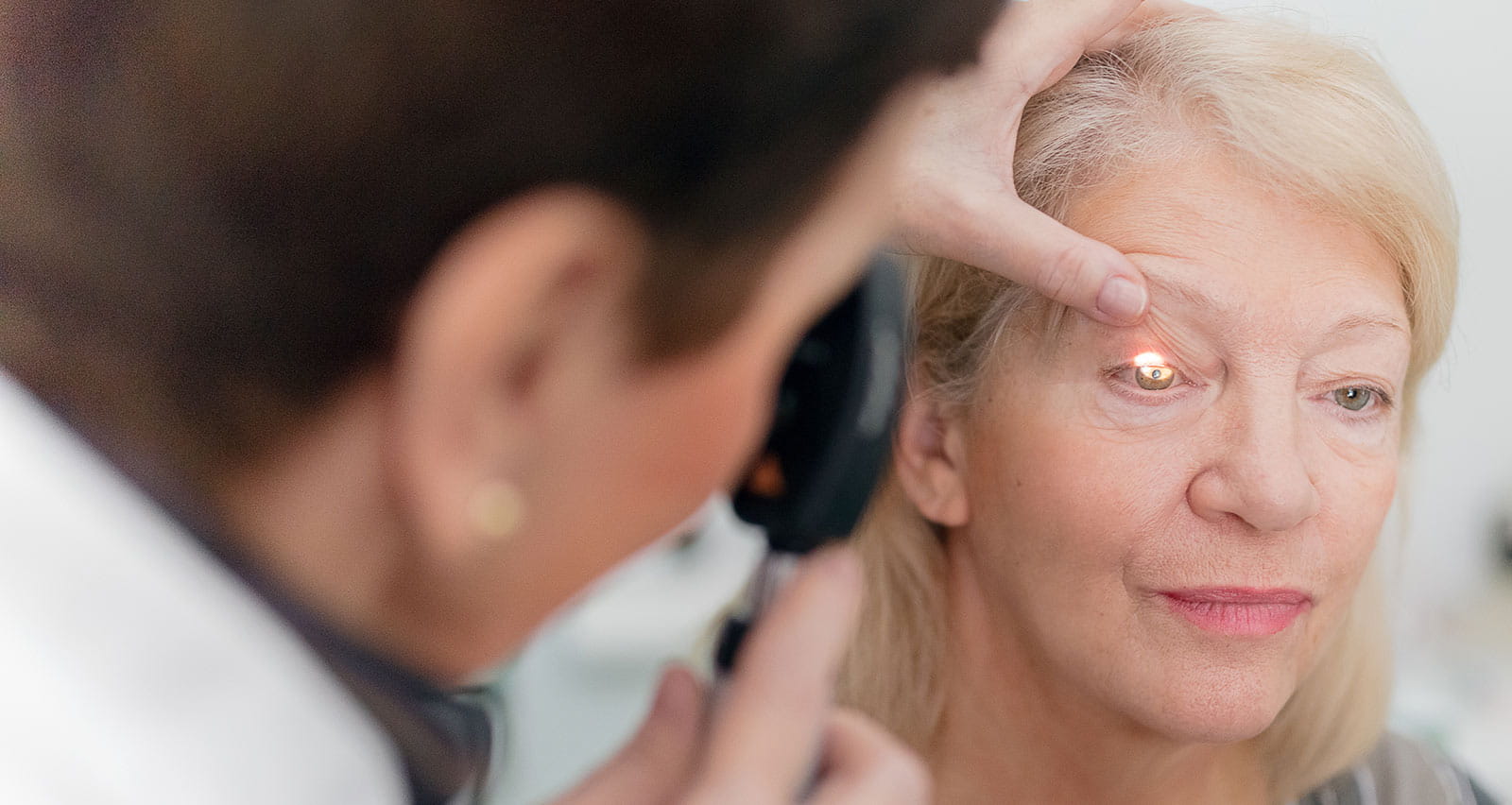 An ophthalmologist looks into a patient’s eye