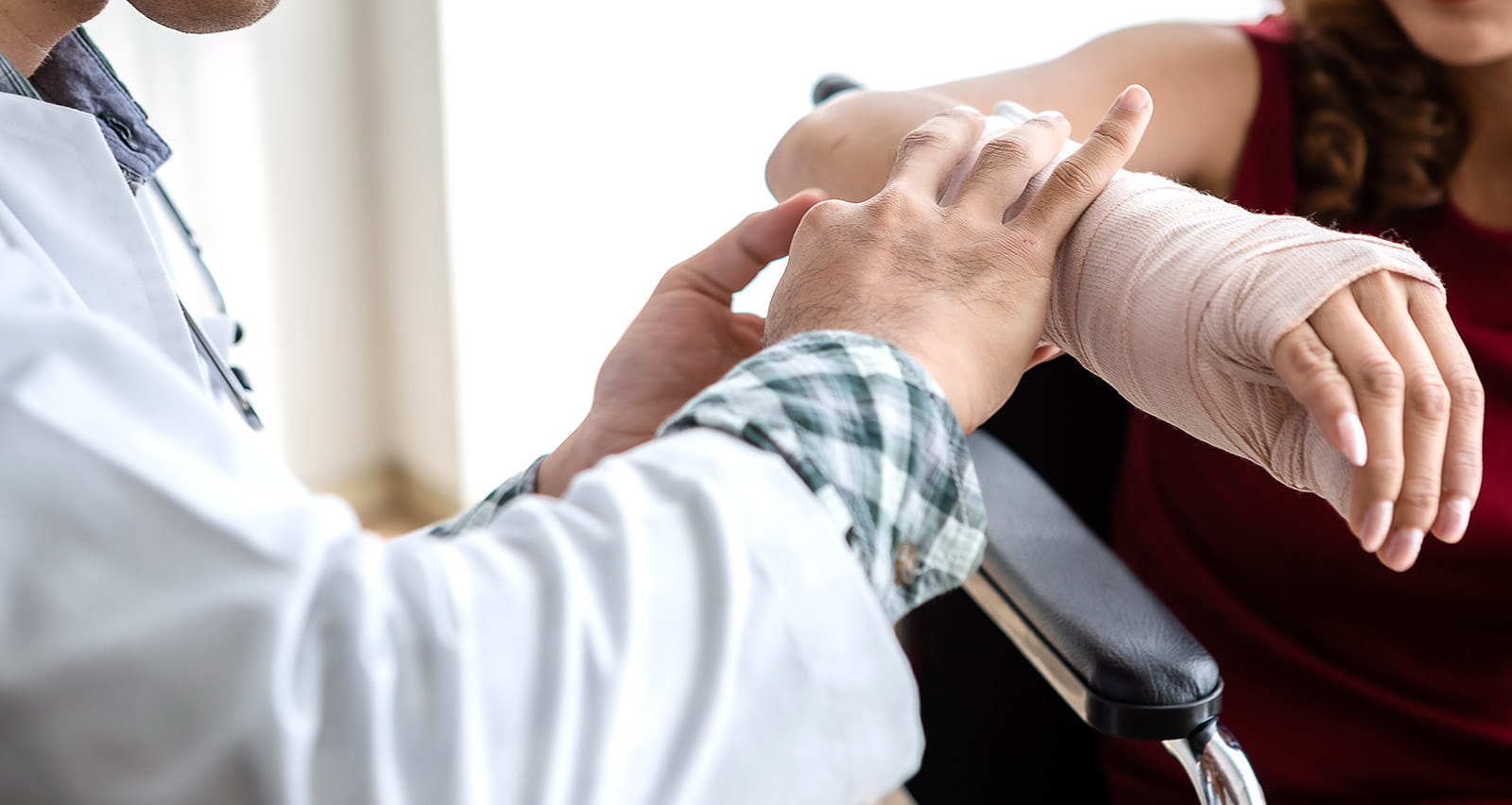 Closeup of doctor wrapping bandages and applying a splint to the arm of a middle-aged female patient
