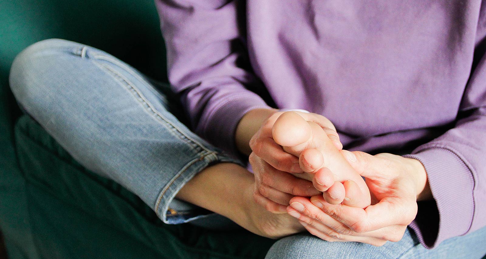 Man sitting on a couch holds his aching toe
