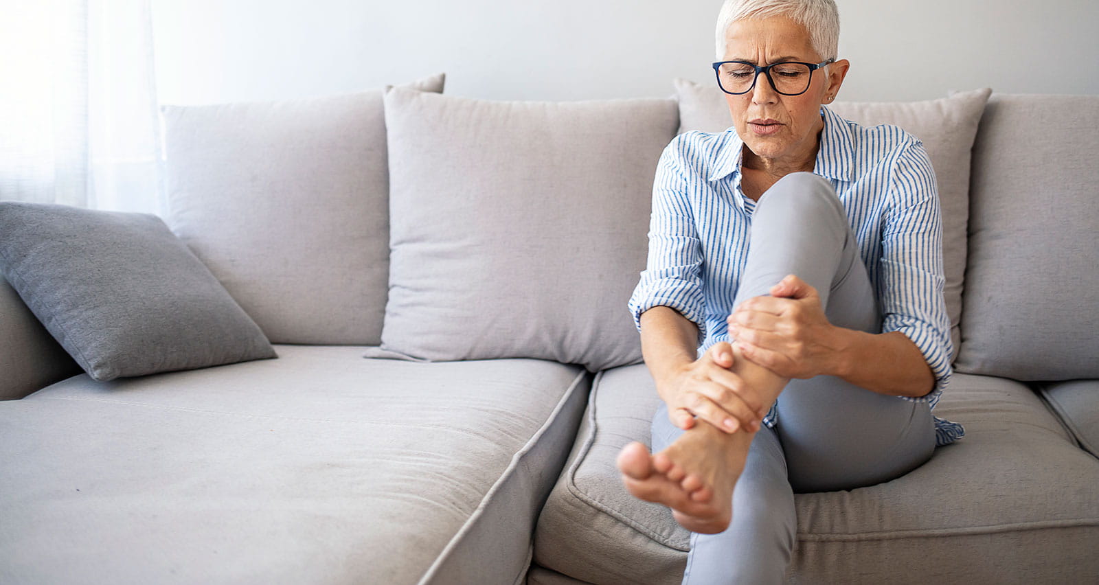 A woman suffering from arthritis in her ankles sits on a couch