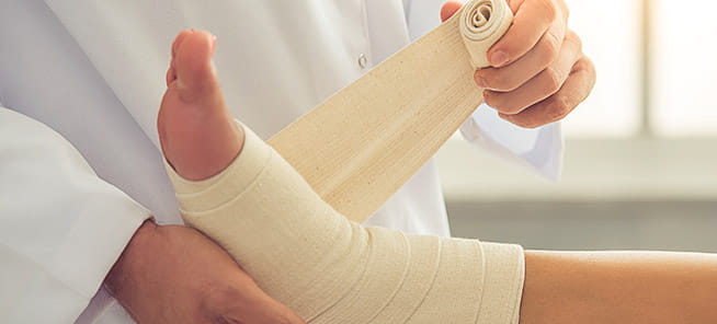Doctor bandaging woman's injured leg