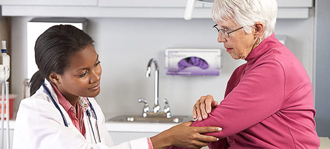 Doctor examining elderly female patient with elbow pain