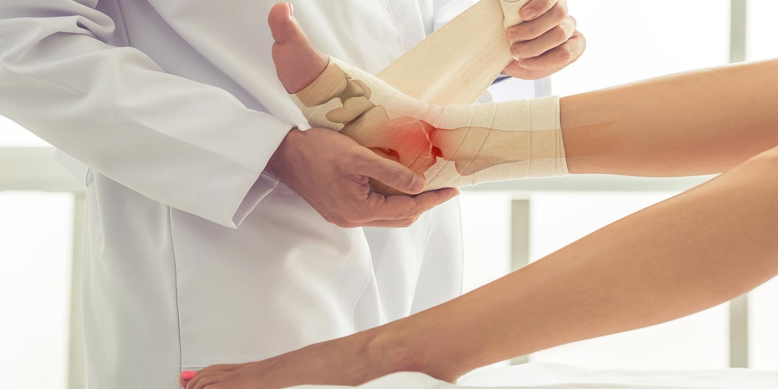 Male physician wrapping bandage around ankle