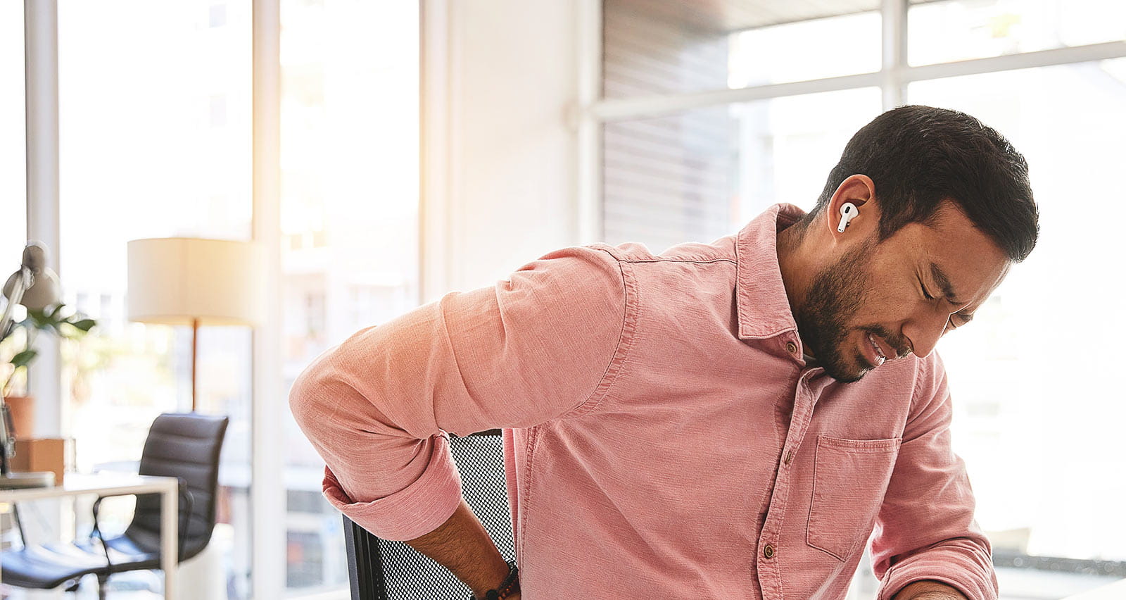 A man winces while clutching his painful back
