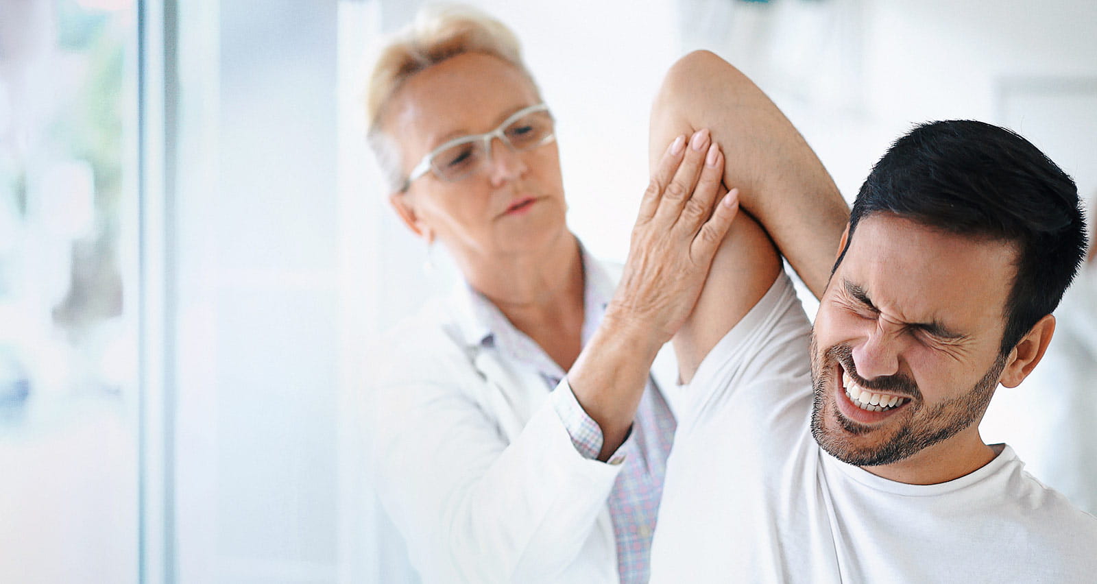 A middle-aged female doctor examining a male experiencing chronic pain