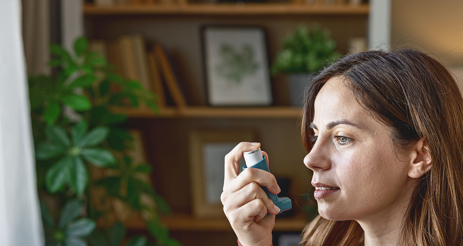 A young woman using her asthma inhaler at home