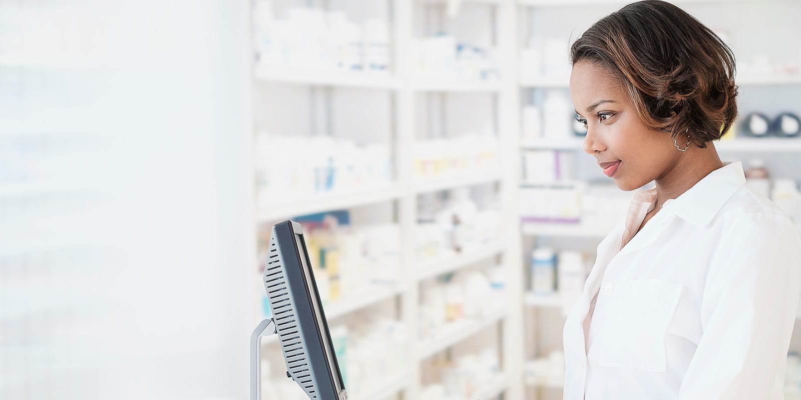 A smiling young pharmacist using computer