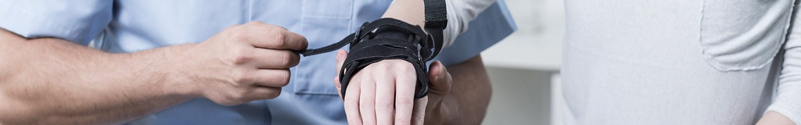 Physiotherapist putting stabilizer on patient's hand.