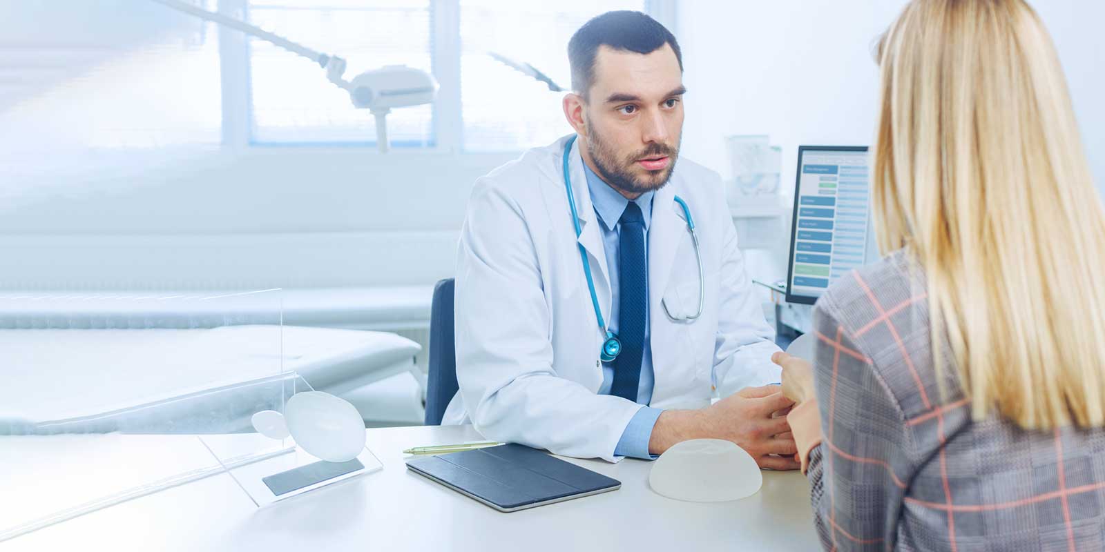 Plastic Surgeon Shows Female Patient Breast Implant Samples for Future Surgery