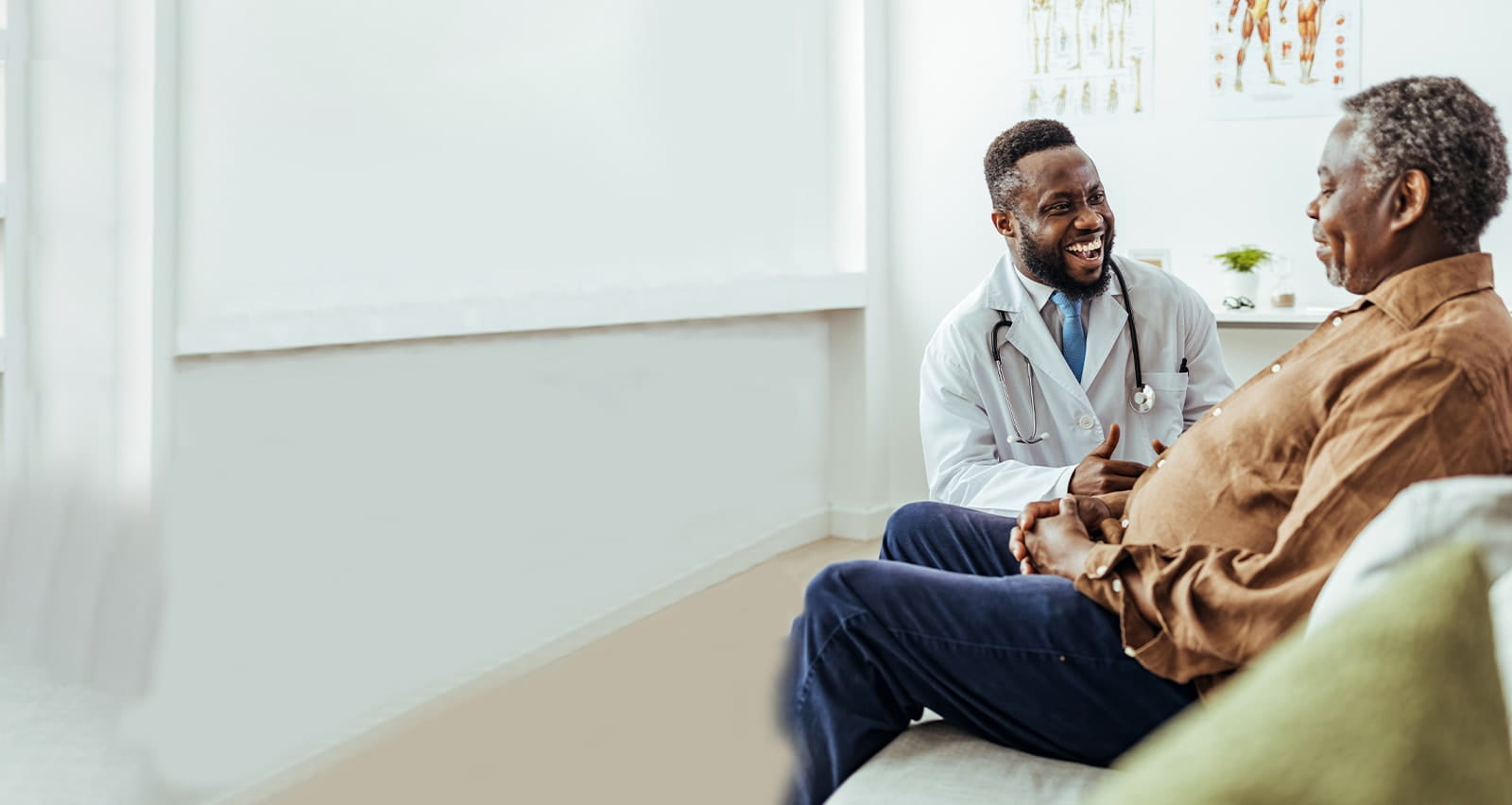 Male doctor of African decent smiles and tries to encourage senior man of of African decent during an appointment
