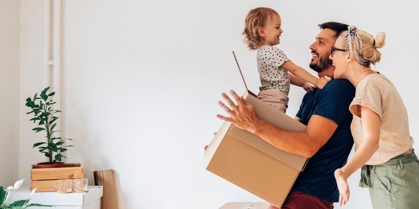 Mother and father holding toddler who climbed into a moving box.