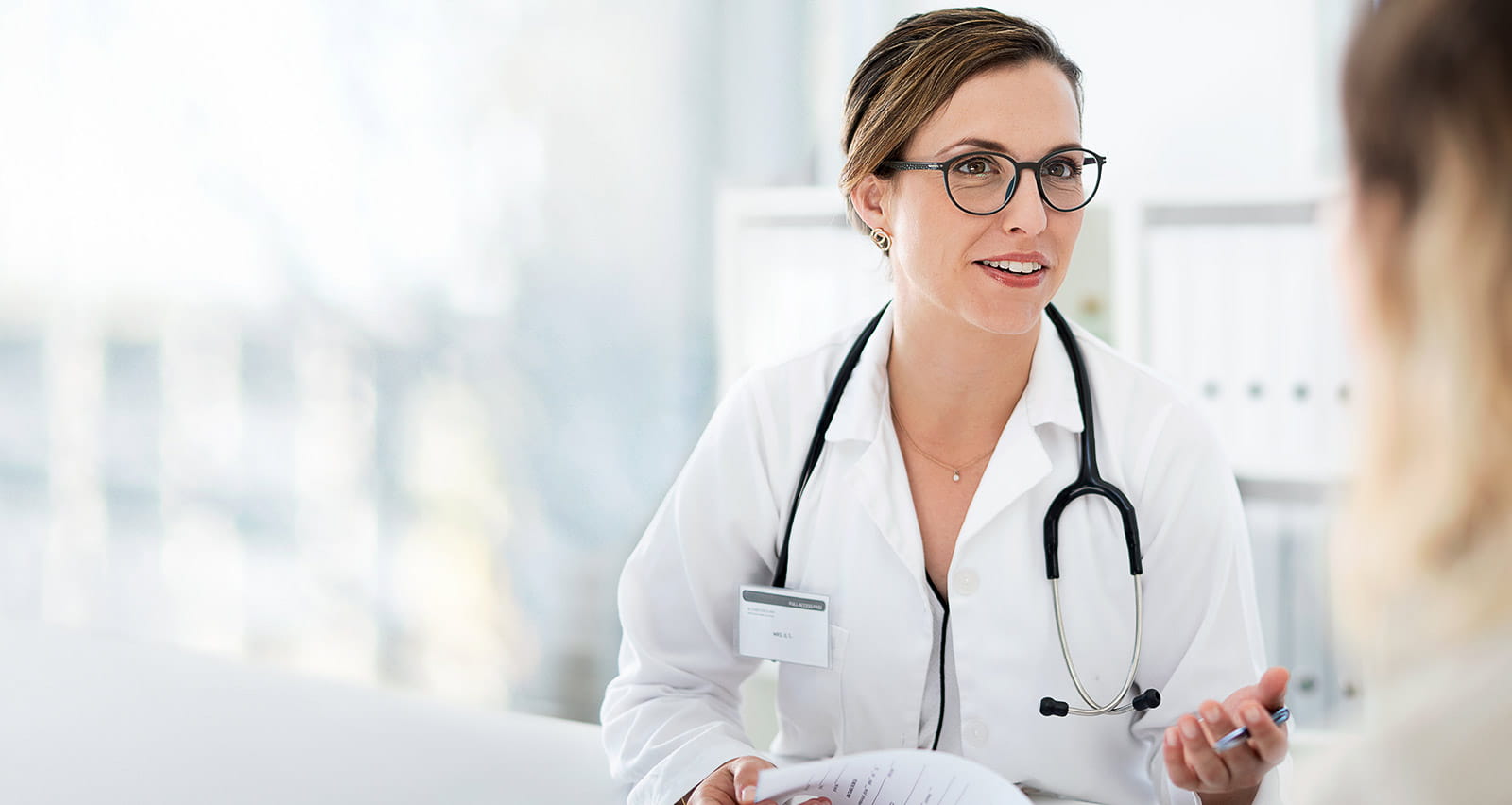 A female primary care doctor consulting with a patient inside her office