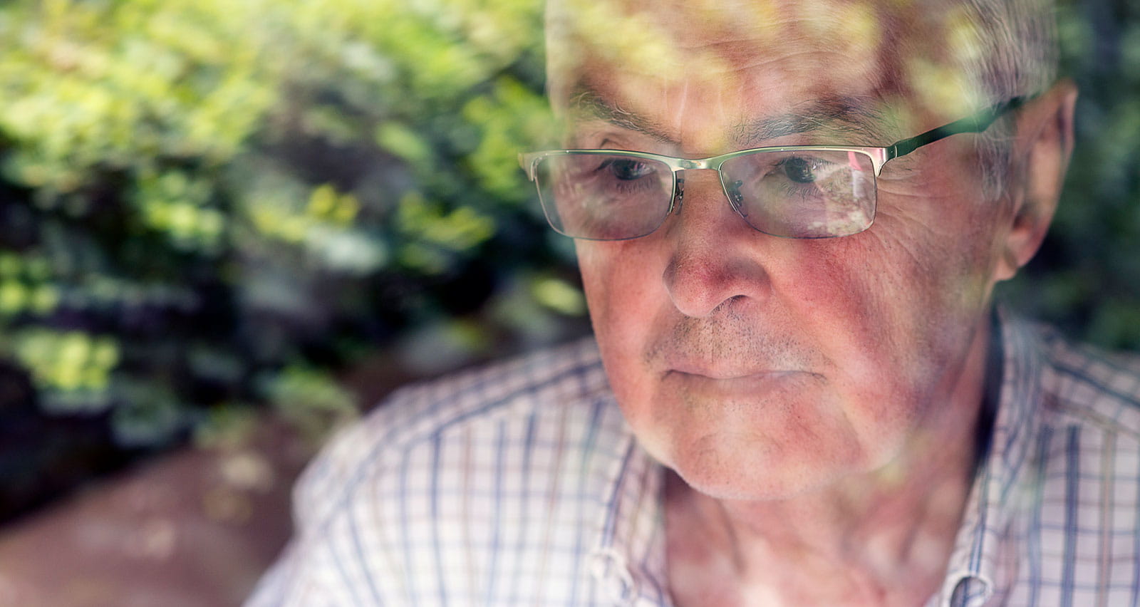 A worried older man is looking through his window