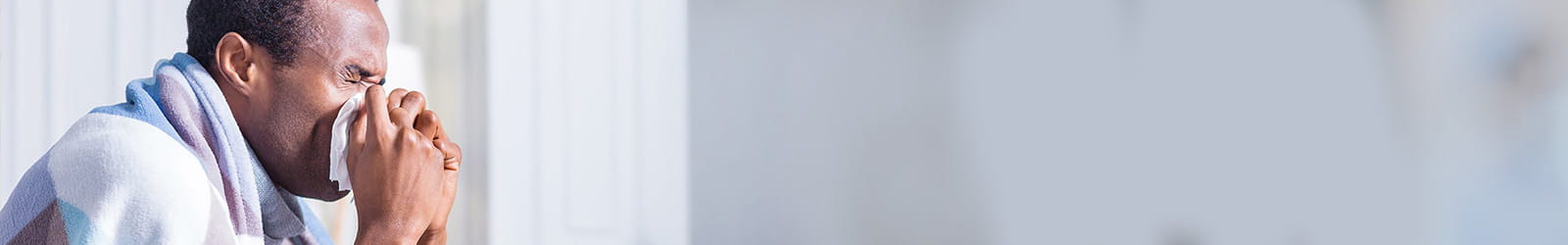 Man sneezing with a blanket around him.