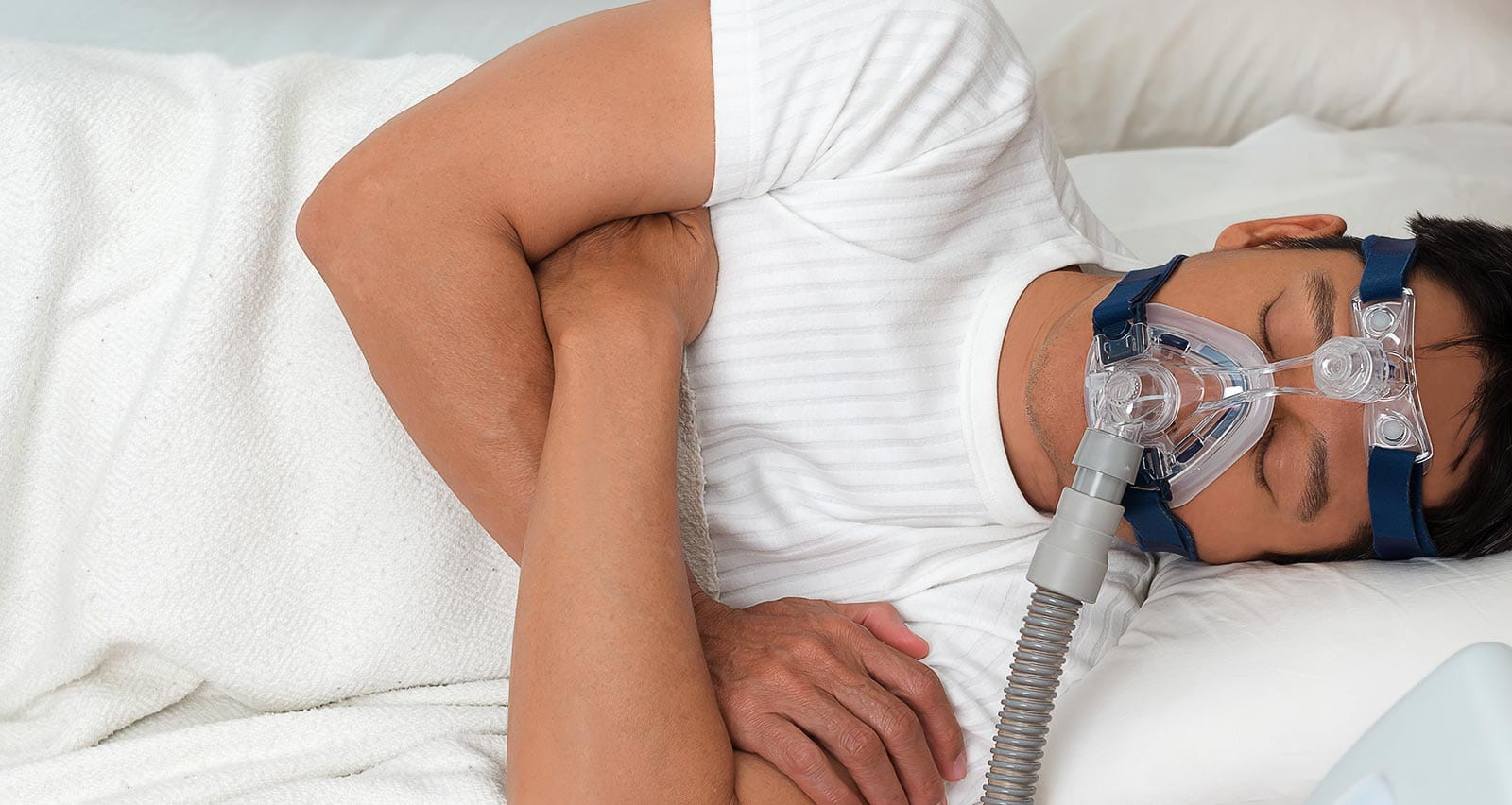 Man in bed  wearing CPAP mask for treatment of sleep apnea