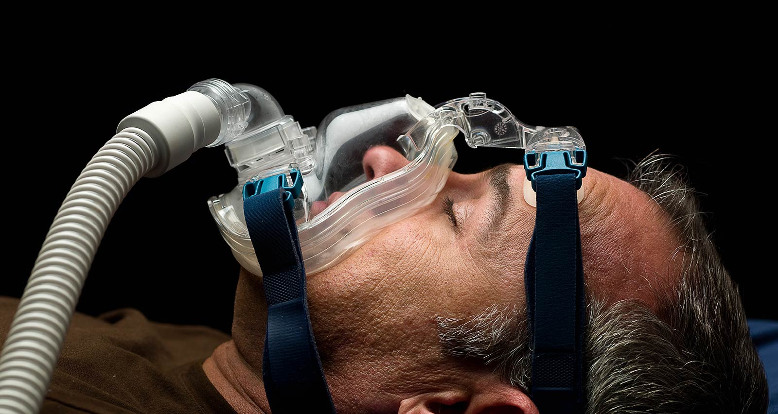 A mature man sleeping, using a mask for sleep disorder treatment