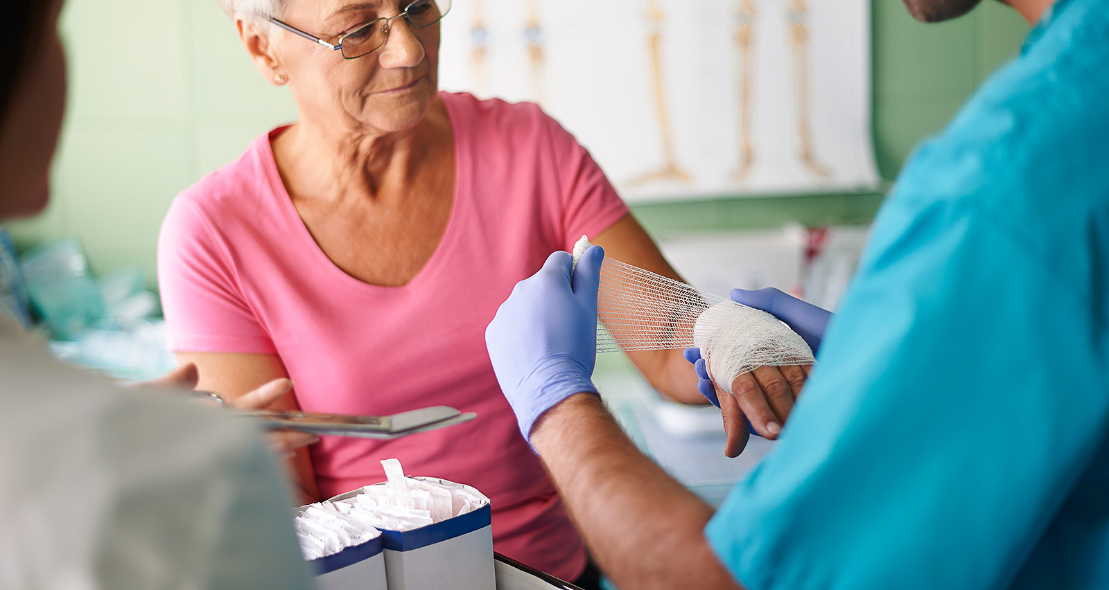 An occupational therapist bandages an older woman’s wrist