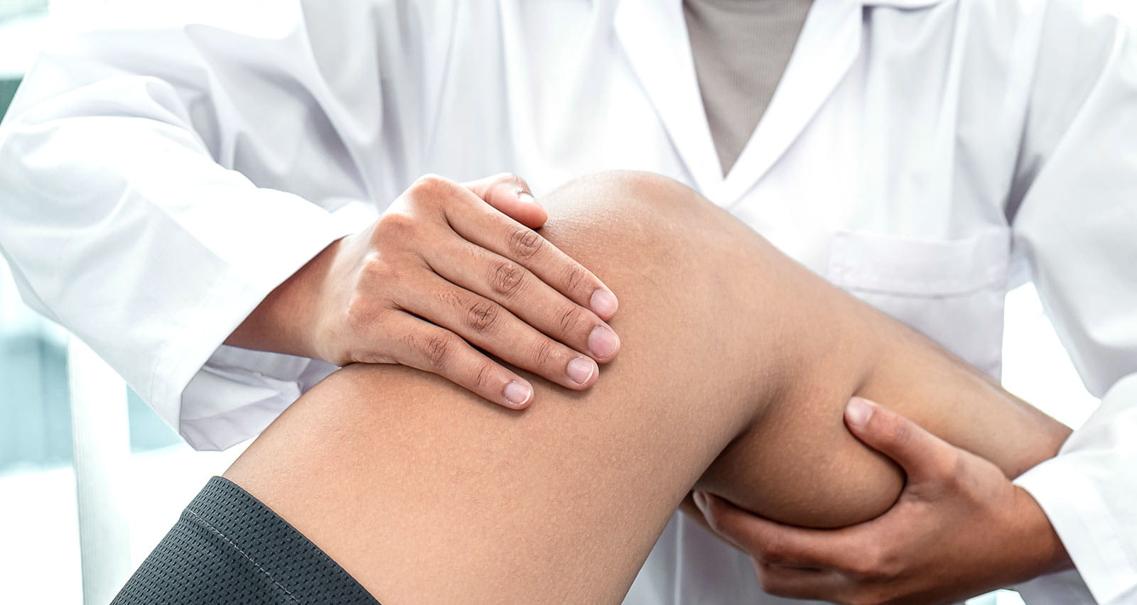 A female physiotherapist examining injured leg of a patient in a Rehabilitation clinic