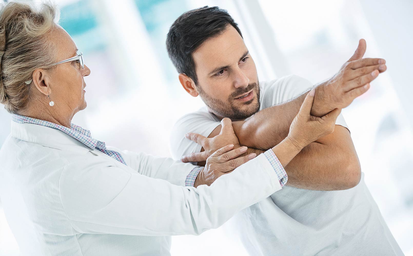Sports medicine physician checks male patient's shoulder