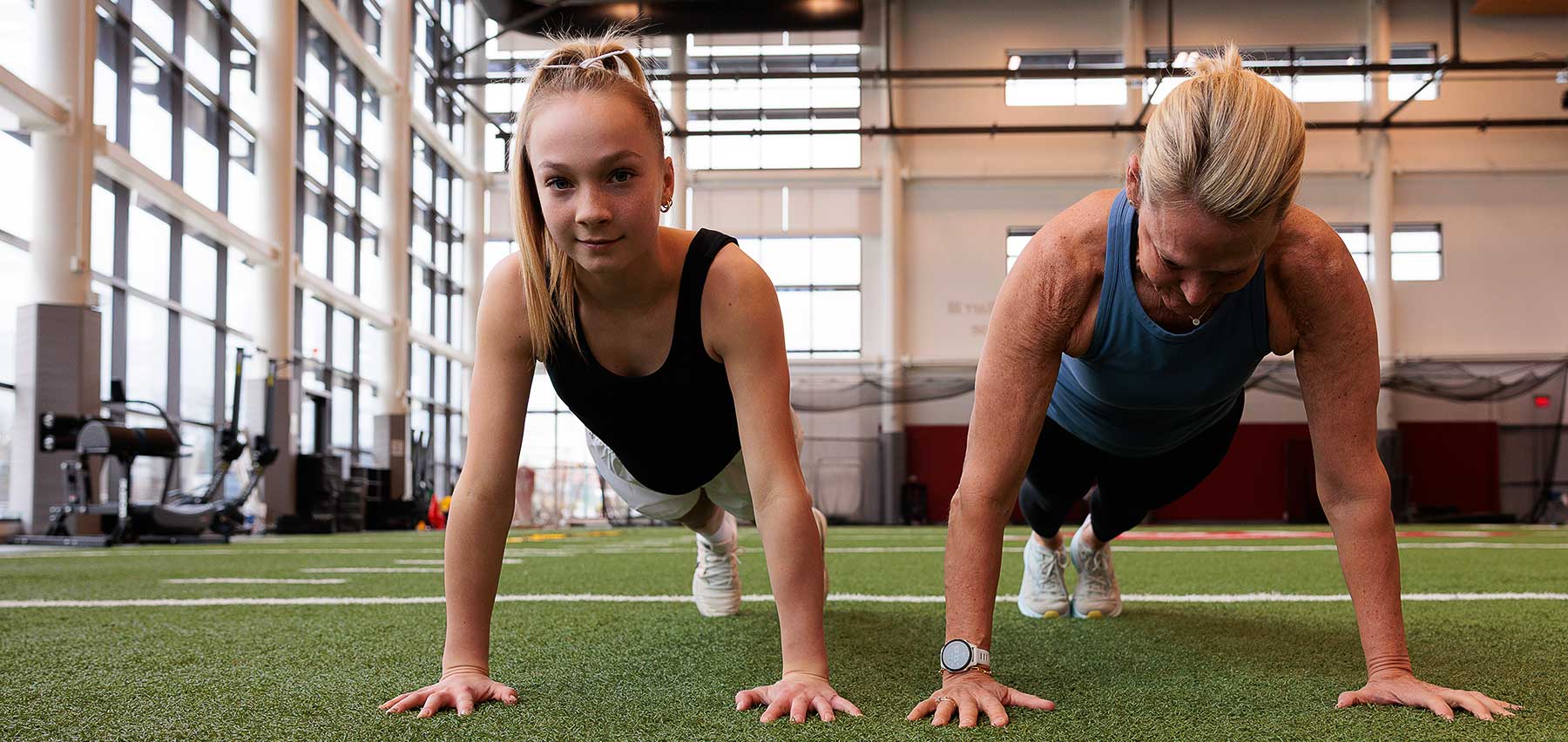 A young woman and her trainer do push-ups on the indoor field at UH Drusinsky Sports Medicine