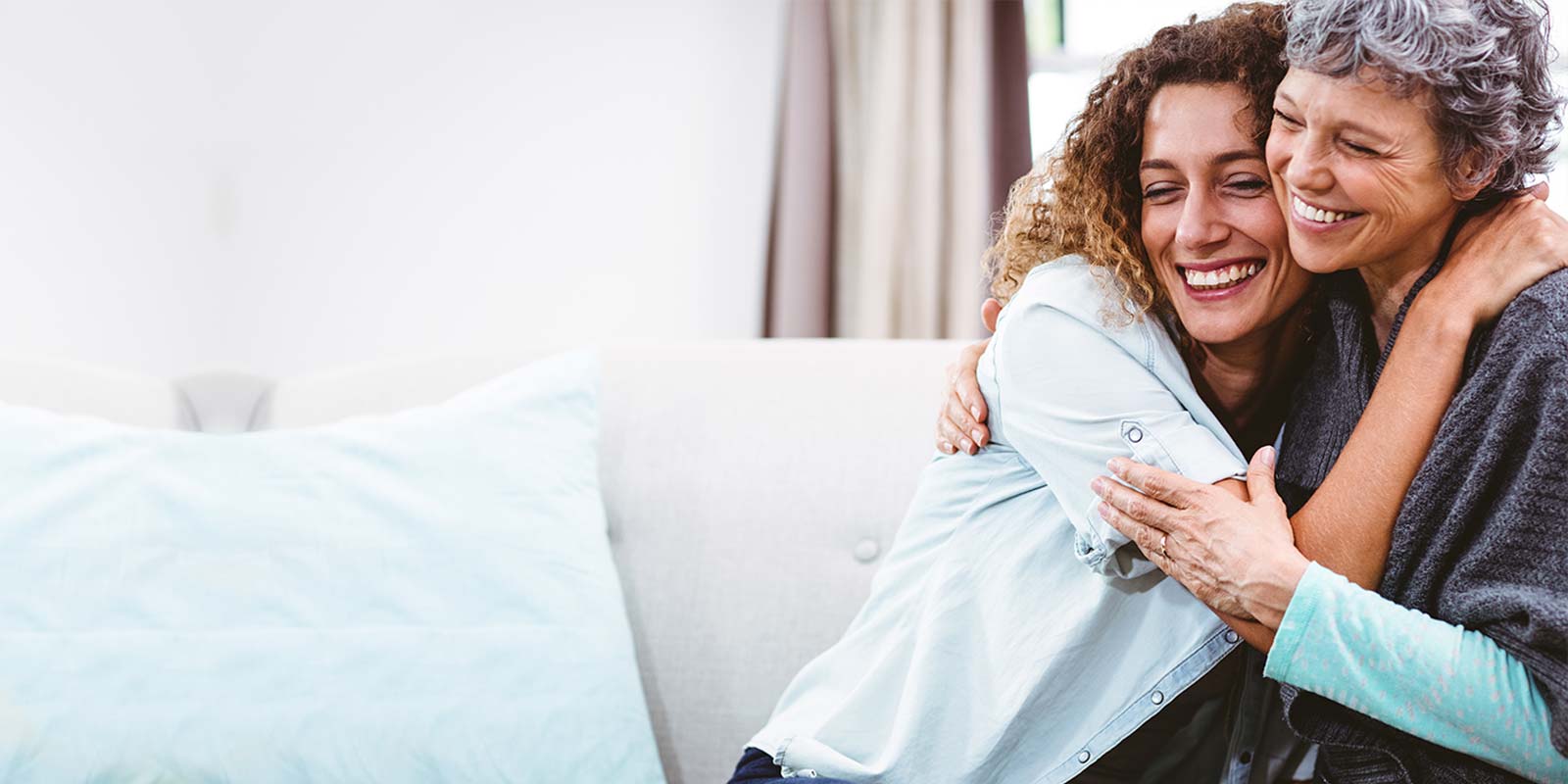 Mother and daughter embracing on couch