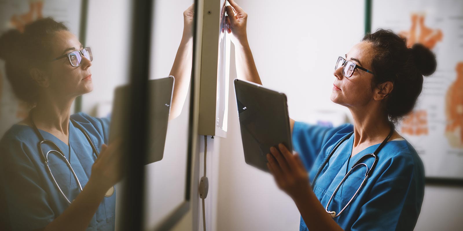 Nurse examining X-rays on tablet device.