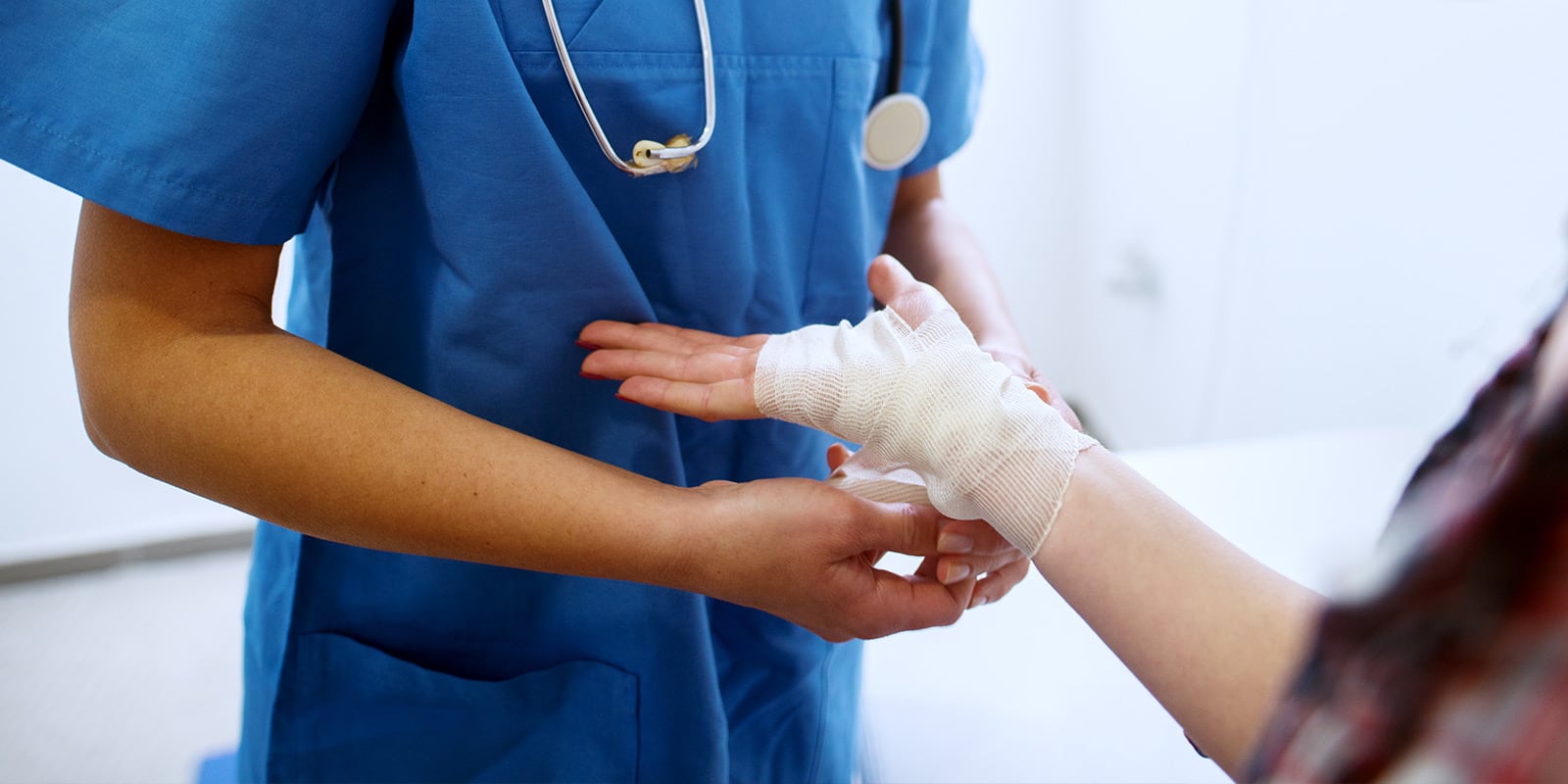 Nurse bandaging woman's hand.