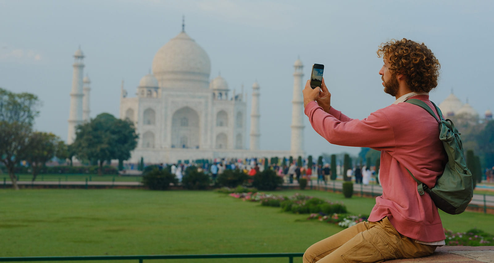 A cheerful man photographing with a smartphone near Taj Mahal in India