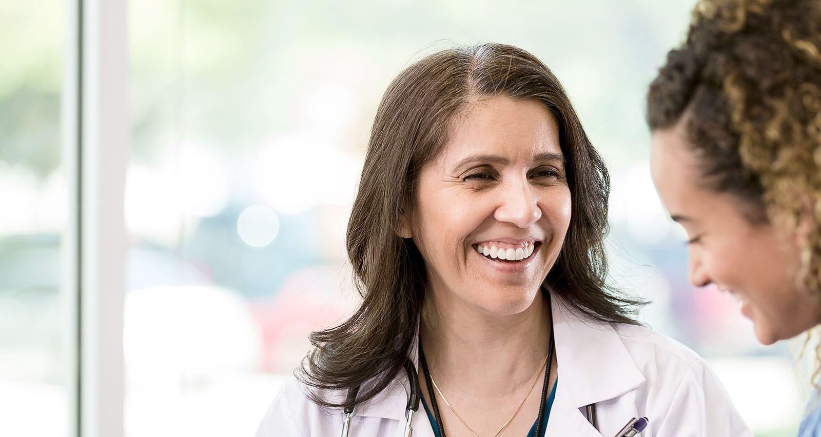 A smiling mature female doctor gives good news to an adult female patient