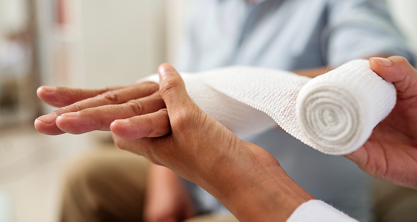 Close up of provider holding and bandaging hand of senior patient at hospital