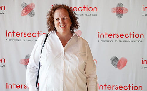 A woman poses in front of the Intersection banner
