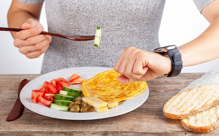 Person with plate of food looking at watch